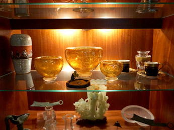 A glass shelf with several bowls and vases on it.